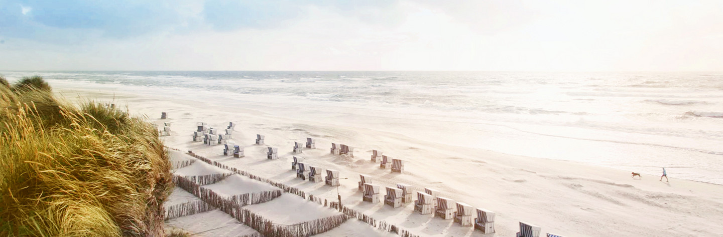 Erhöhter Blick auf Strandkörbe am Sylter Strand, die Nordsee am Horizont und rechts
