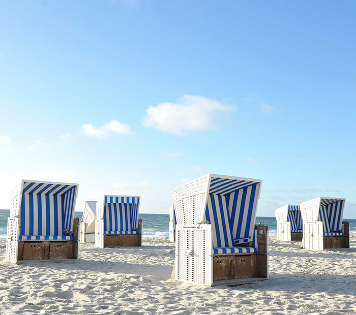 Weiße Strandkörbe vor blauem Himmel
