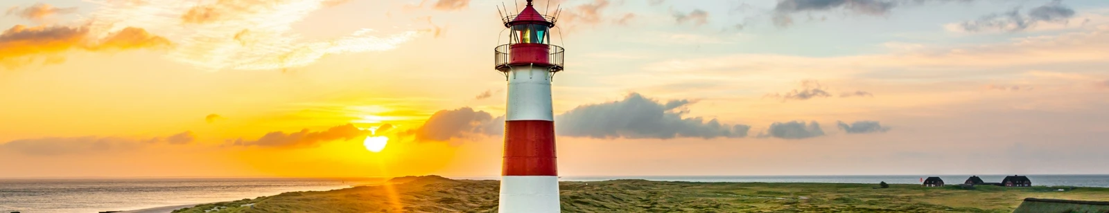 Rot-weißer Leuchtturm List auf Sylt vor untergehender Sonne im goldenen Licht