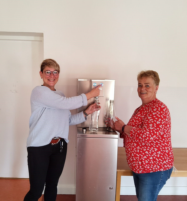 Zwei Mitarbeiterinnen der Kita testen den neuen Trinkwasserspender