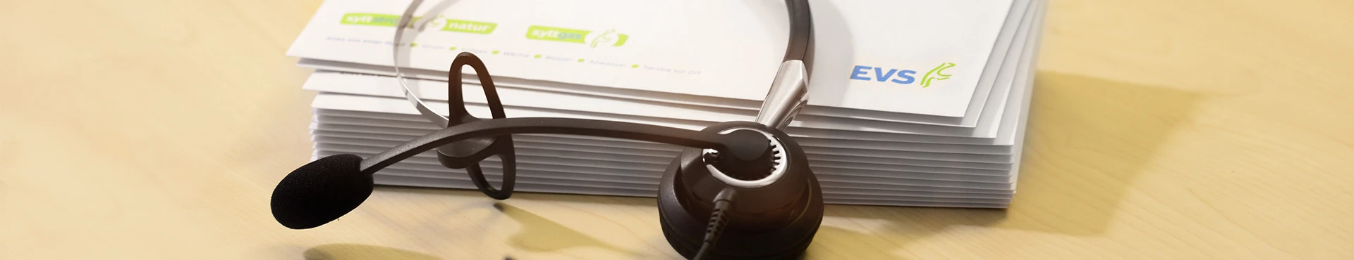 Headset liegt auf Stapel Geschäftspapieren mit EVS-Logo
