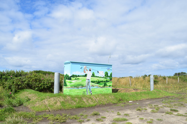Eine Trafostation bemalt mit einem Golfer